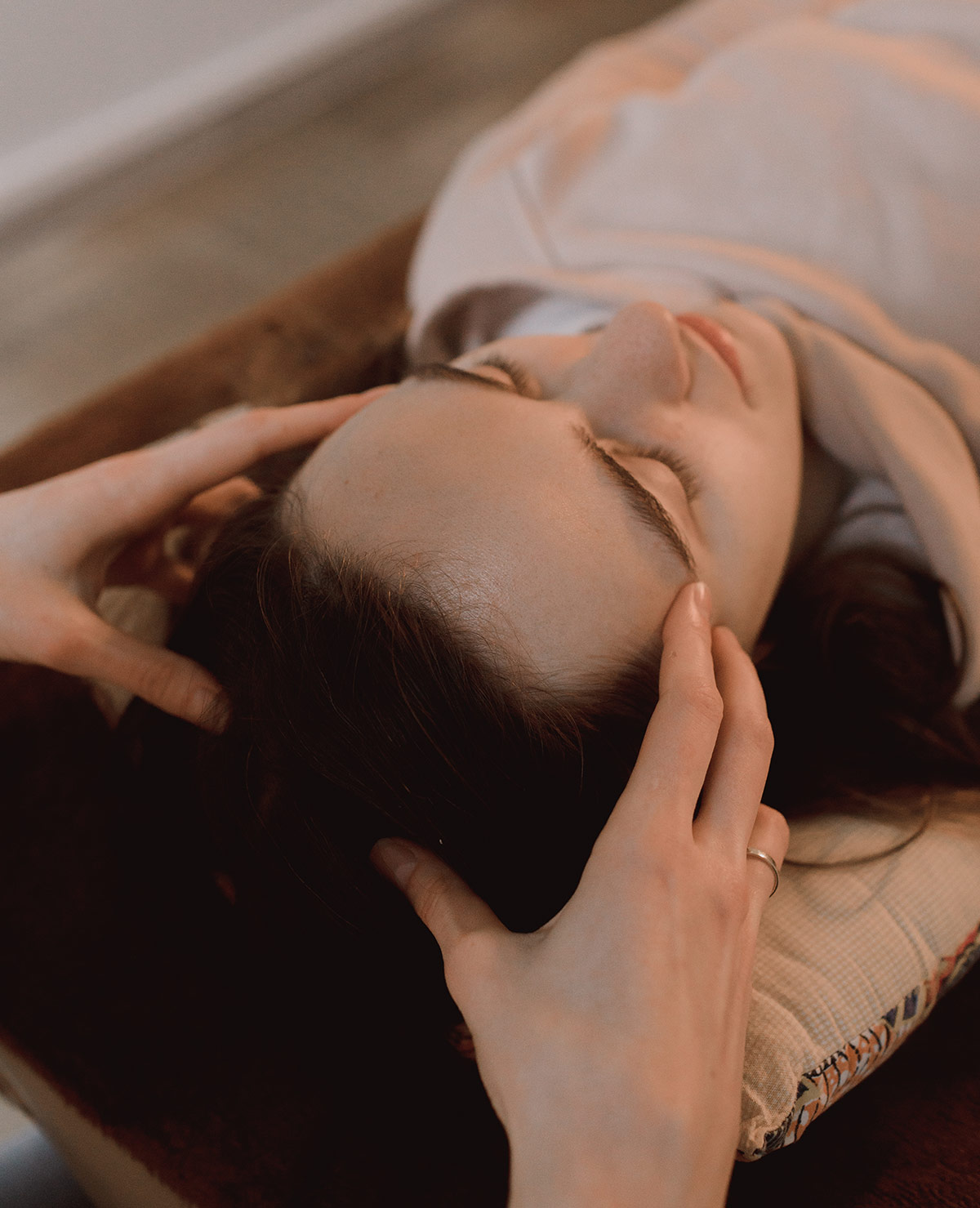 Practitioner gently supporting a client’s head during a biodynamic craniosacral therapy session